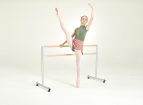 A ballet dancer with one arm and leg raised on a Freestanding and Portable Ballet Barre.